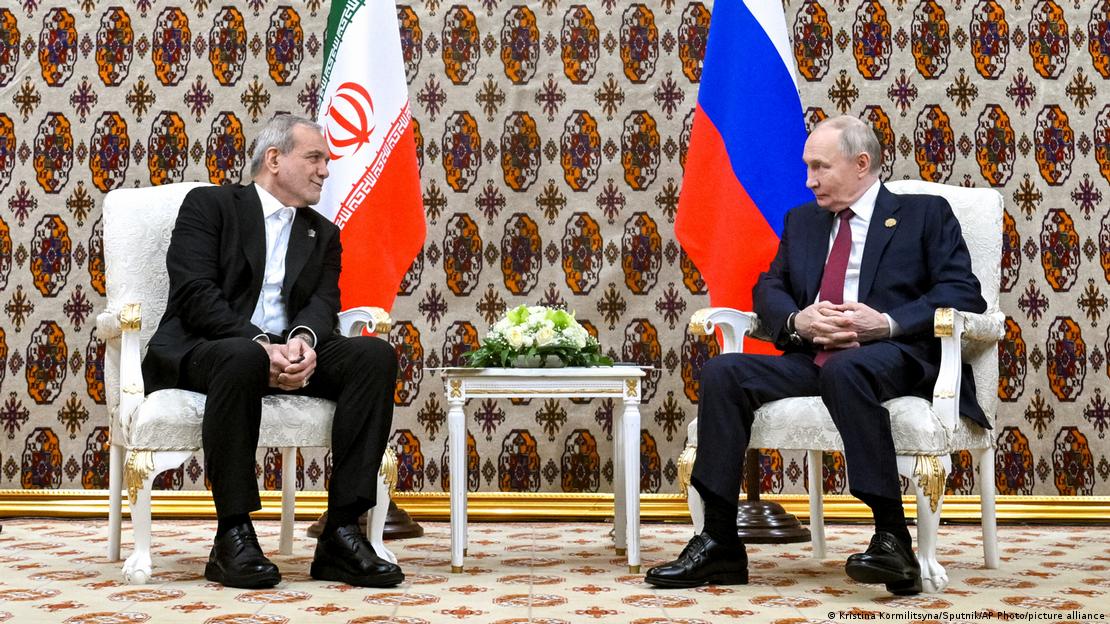 İran Cumhurbaşkanı Mesud Pezeşkiyan (solda) ve Rusya Devlet Başkanı Vladimir Putin yan yana oturuyor. İkilinin yüzleri birbirlerine dönük, arkalarında ülkelerinin bayrakları görülüyor